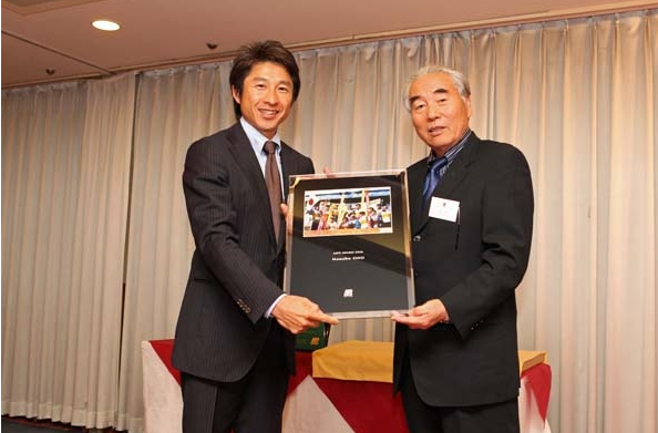 当協会会長水谷章人より故小野学氏に代わり荻原健司氏に記念の写真盾を贈呈